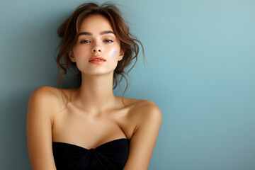 Fototapeta premium A woman with a black dress and a black bra is standing in front of a blue wall. She has a smile on her face and her hair is pulled back