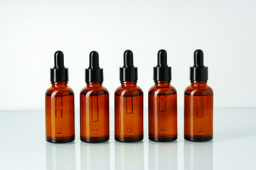 Row of various brown glass dropper bottles isolated on white background