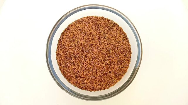 Fenugreek seeds in a glass bowl isolated rotating on white background, a glass bowl full of Fenugreek seeds top view, close up, herbs and spices.