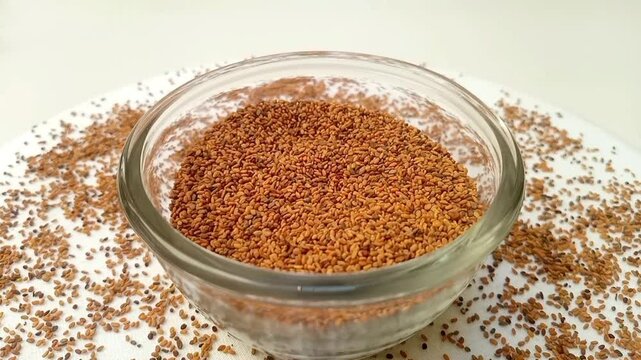 Fenugreek seeds in a glass bowl spices spilled around it, rotating on white background, center frame, zooming in, close up, herbs and spices.