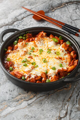 Korean Style Fire Chicken Buldak With Cheese closeup on the pan on the table. Vertical