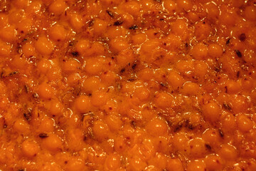 Close-up of sea buckthorn jam: bright orange sea buckthorn berries in thick syrup, shiny texture