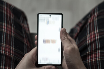 A man is scrolling through the news feed: sitting with a phone in his hands, looking intently at the screen, expressing anxiety