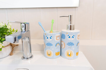 Two toothbrushes in container on sink in kid bathroom. Bathroom interior and accessories concept