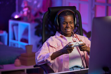 Portrait of African American girl playing video games and smiling while holding gamepad