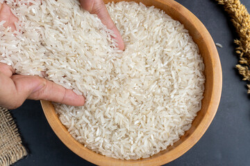 close up of top view of hand pouring rice into wooden bowl on table