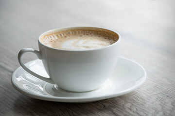 Cup of hot cappuccino coffee on table
