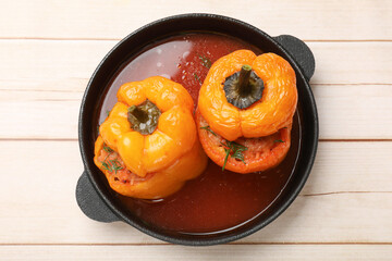 Tasty stuffed peppers in pan on light wooden table, top view