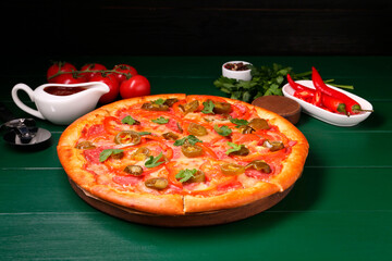 Delicious pizza Diablo, ingredients and cutter on green wooden table