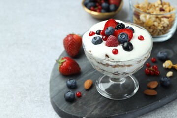 Tasty yogurt with fresh berries, granola and nuts on gray table, closeup. Space for text
