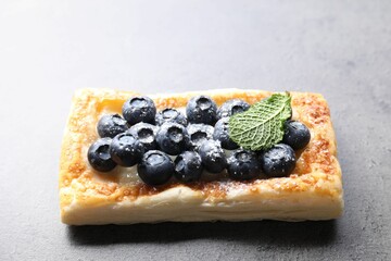 Tasty puff pastry with blueberries and mint on grey table, closeup