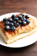 Tasty puff pastry with blueberries on wooden table, closeup