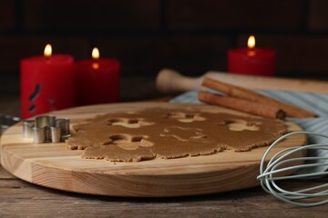 Raw dough, cookie cutter, whisk and burning candles on wooden table, closeup