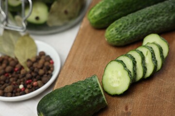 Board with fresh cut cucumber and spices on table, closeup. Preparation for pickling