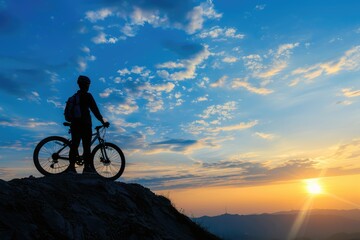 Fototapeta premium Silhouette cyclist standing with bicycle on mountain peak against sky