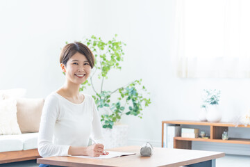 自宅で机に向かい笑顔でカメラを見る女性