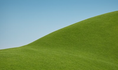 Fototapeta premium Zielone, trawiaste wzgórze na tle błękitnego nieba