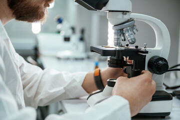 Professional laboratory worker is using microscope