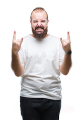 Naklejka premium Young caucasian hipster man wearing casual t-shirt over isolated background shouting with crazy expression doing rock symbol with hands up. Music star. Heavy concept.