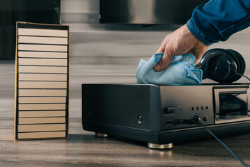 Man doing general clean up and wiping old audio boombox. Meticulously maintained audio equipment in...