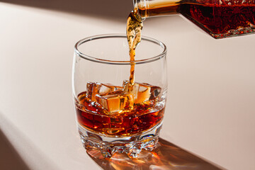 Whiskey is poured into a glass with ice