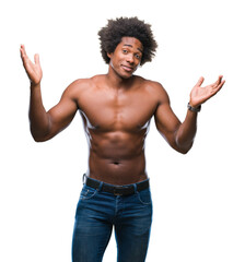 Fototapeta premium Afro american shirtless man showing nude body over isolated background clueless and confused expression with arms and hands raised. Doubt concept.
