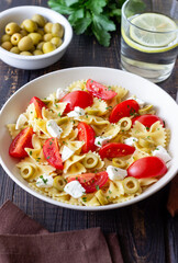 Farfalle pasta with white cheese, tomatoes and olives. Healthy eating. Vegetarian food.