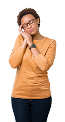 Young beautiful african american woman wearing glasses over isolated background sleeping tired dreaming and posing with hands together while smiling with closed eyes.