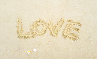 Writing in light yellowish sand of the word love. Tropical island on clean sea sand. for Valentine's Day Affection, wedding, longing Photographed from above in close-up Suitable for vacation postcards