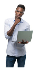 Young african american businessman using computer laptop serious face thinking about question, very confused idea