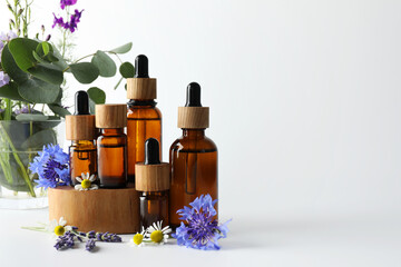Aromatherapy. Different essential oils, eucalyptus leaves and flowers on white background, space...