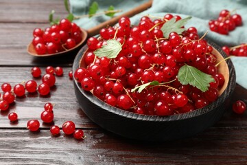 Fresh red currants and green leaves on wooden table, closeup
