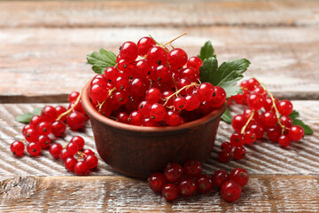 Fresh red currants in bowl on wooden table, closeup