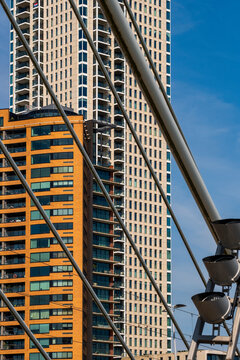 A view of modern skyscrapers with different fa&ccedil;ade styles is seen through the cables and supports of a bridge, combining engineering magnificence and urban architecture  in Rotterdam