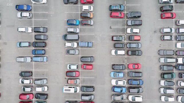 Top-down flyover of a busy UK carpark with numerous parked cars, highlighting the organized parking layout