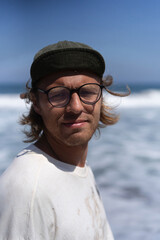 Portrait of a young man in a cap, squinting from the sun.