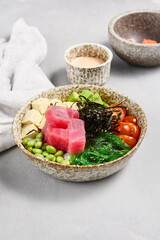 Tuna Poke Bowl with Edamame, Avocado, and Tomatoes on Modern Gray Background