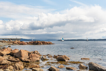 Rocky BC shoreline overlooking sailboats on the Pacific ocean.