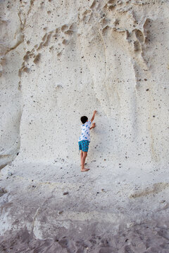 Child's adventure: climbing white rock face on the beach vertical