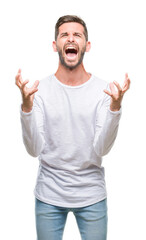 Fototapeta premium Young handsome man over isolated background crazy and mad shouting and yelling with aggressive expression and arms raised. Frustration concept.