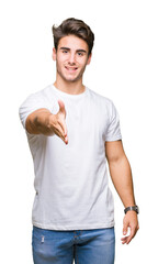Young handsome man wearing white t-shirt over isolated background smiling friendly offering handshake as greeting and welcoming. Successful business.