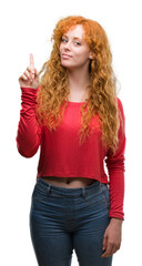 Young redhead woman surprised with an idea or question pointing finger with happy face, number one