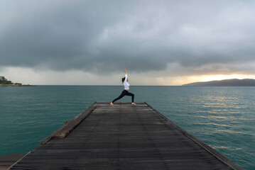 Young healthy woman practicing yoga on the bridge in the nature