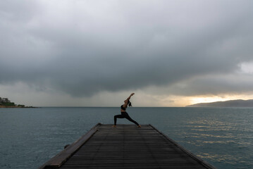 Young healthy woman practicing yoga on the bridge in the nature