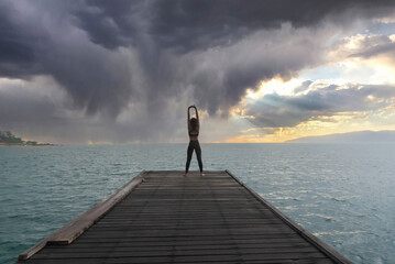 Young healthy woman practicing yoga on the bridge in the nature