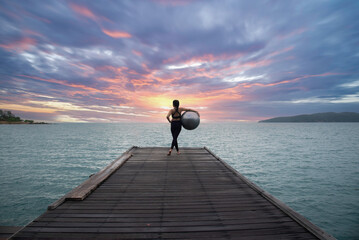 Young healthy woman practicing yoga on the bridge in the nature