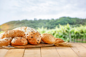 Fresh baked buns on wooden table on a background of green fields. Copy space for products. Countryside concept and image for products montage display