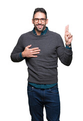 Young handsome man wearing glasses over isolated background Swearing with hand on chest and...