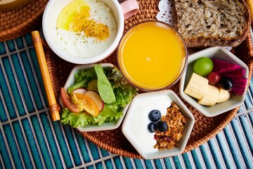 A delicious vegetarian breakfast set of various healthy food in wickerwork tray on blue tile background