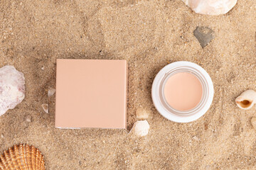 A plain box is placed on sandy beach with seashells surrounding it, creating a minimalistic yet eye-catching composition suitable for various purposes.